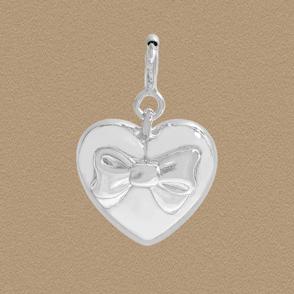 Polished sterling silver heart pendant with a bow motif hanging from a small bail.