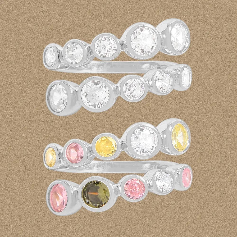 Three sterling silver bezel-set gemstone rings stacked together on a warm tan background.