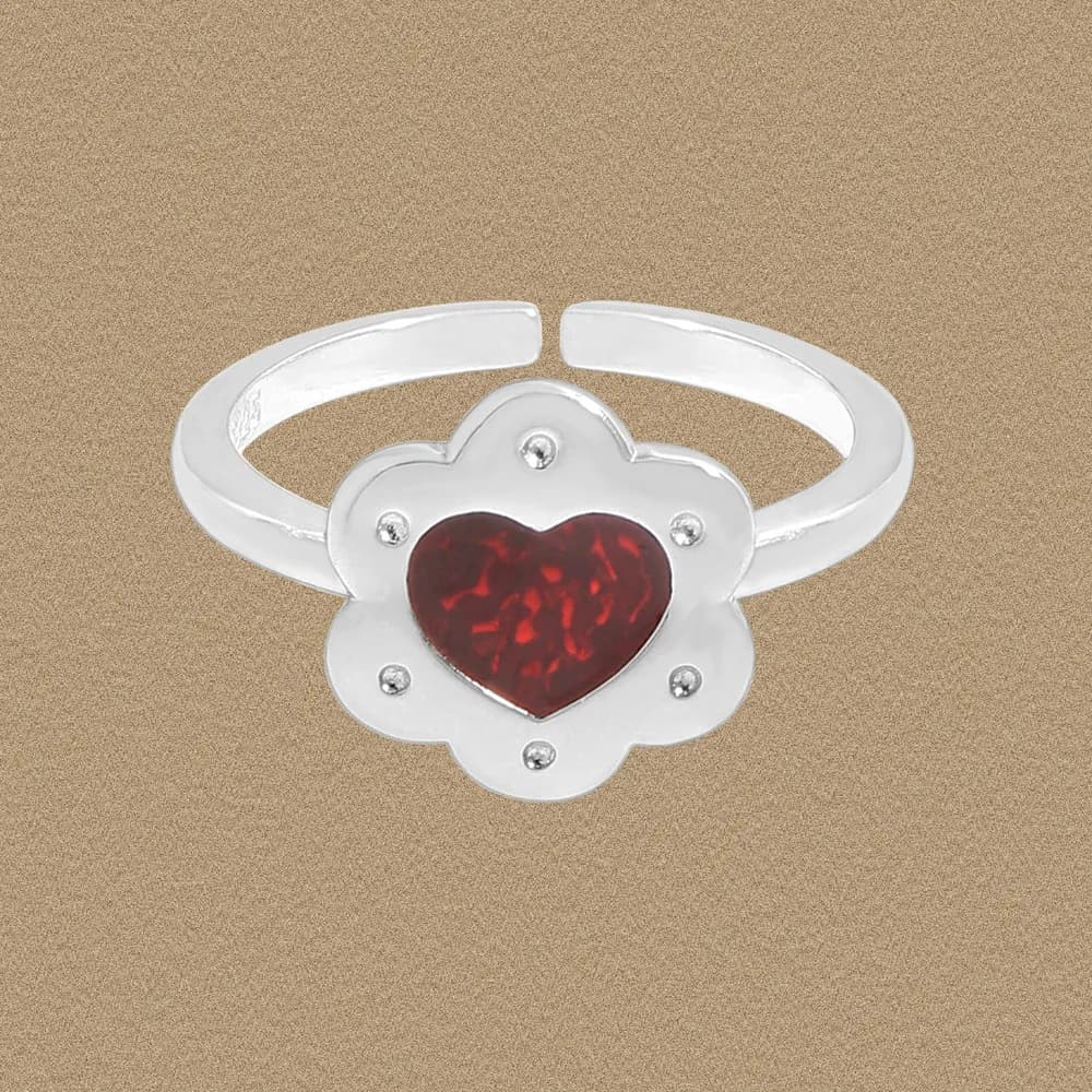 Polished sterling silver ring with a flower-shaped setting and a red heart gem at the center.