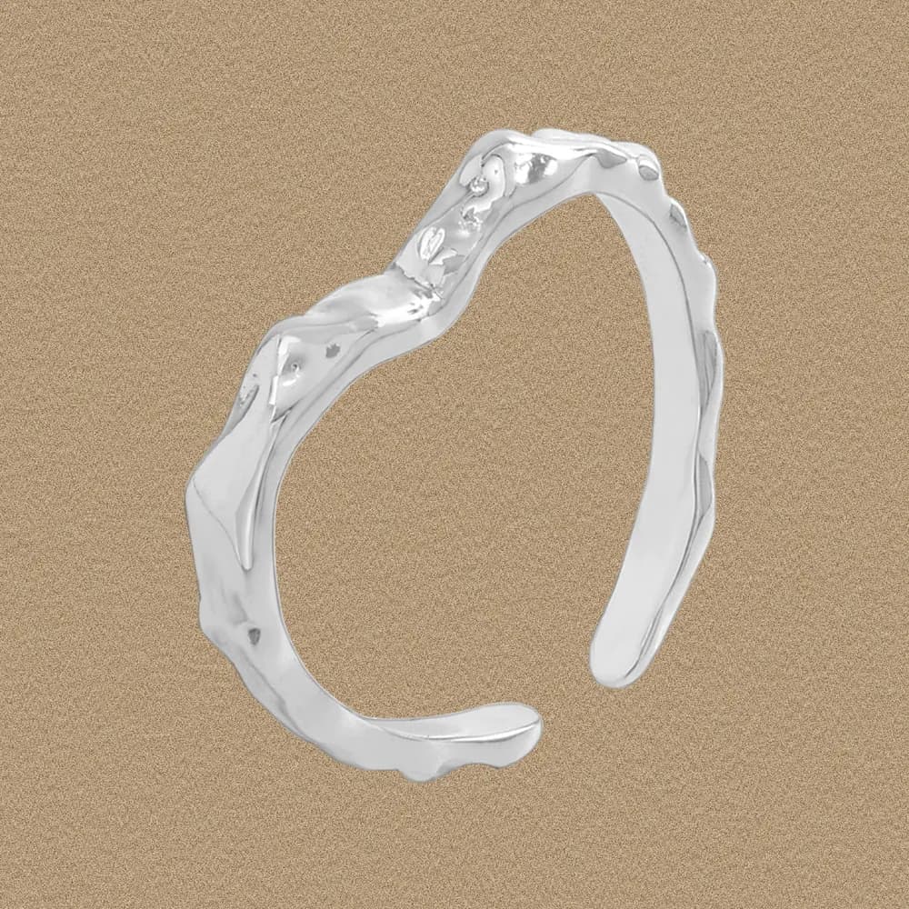 Polished sterling silver open ring with organic wavy texture on a sand-toned background.