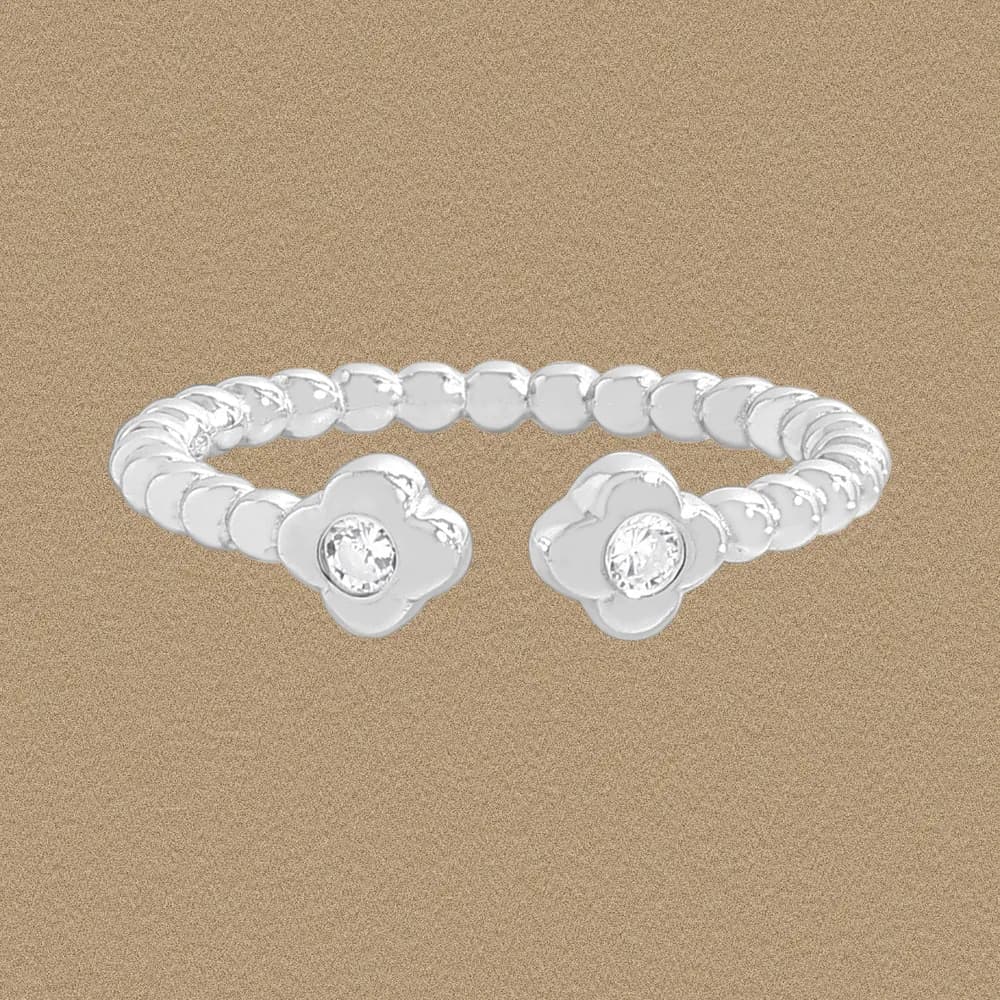 Polished sterling silver ring with two flower motifs each holding a clear center stone on a beaded band.