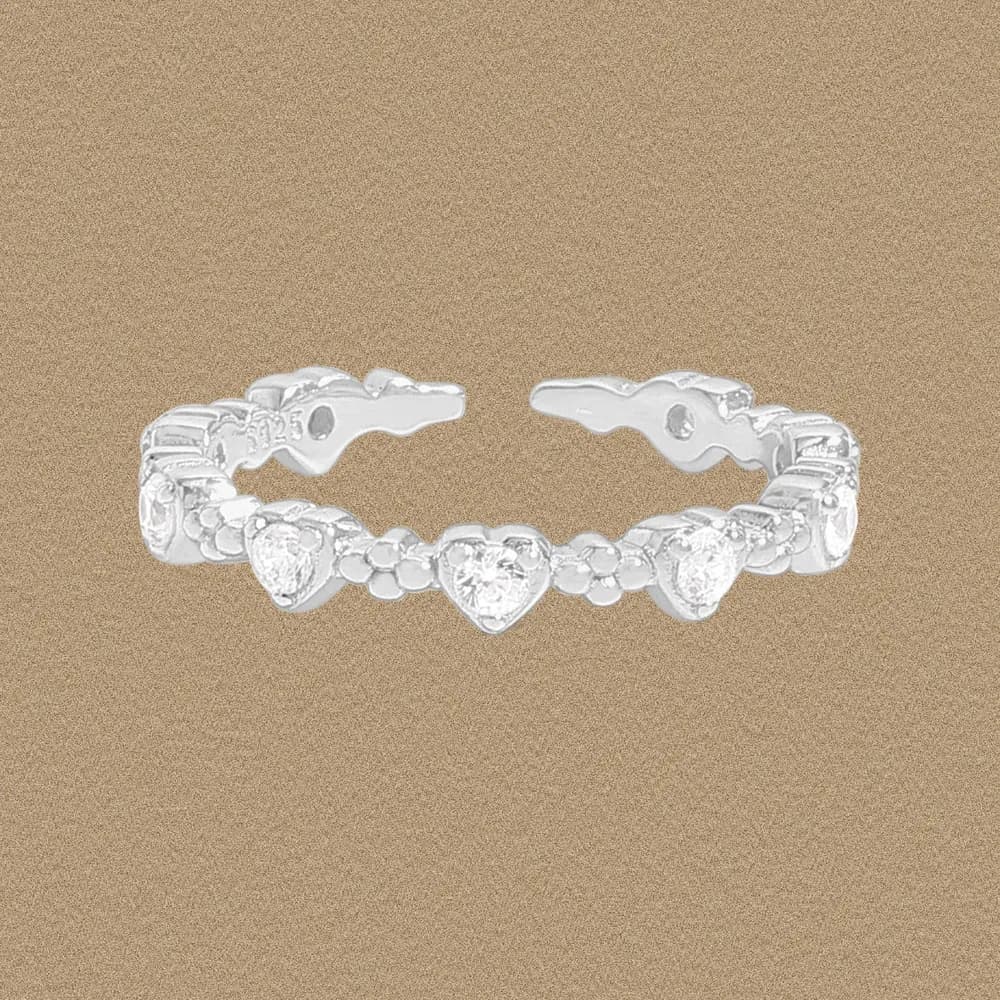 Polished sterling silver ring with a central heart and surrounding floral clusters on a warm background.