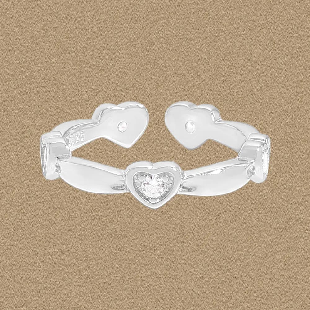 Polished sterling silver ring with a heart-shaped center stone and open heart ends on a warm beige background.