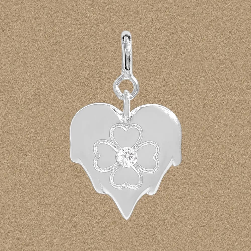 Polished sterling silver heart pendant with a flower design and central stone on a warm background.