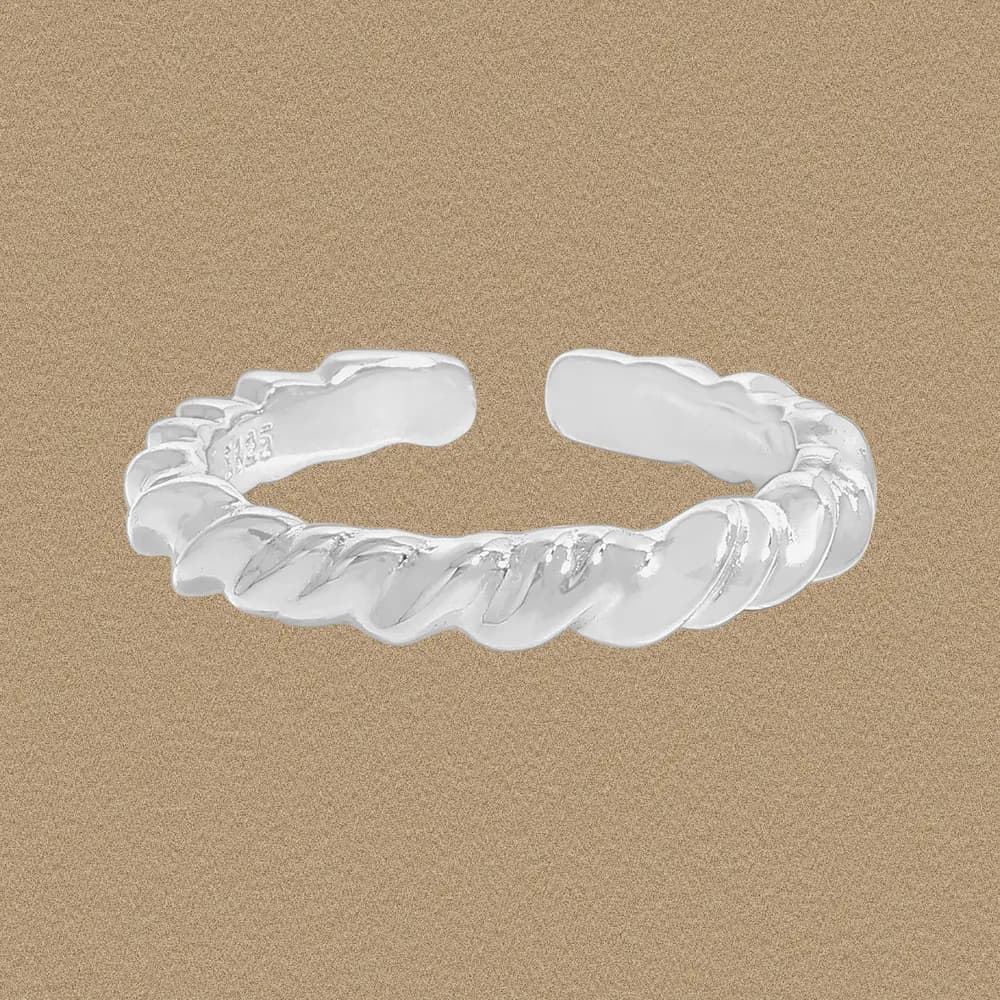 Polished sterling silver twisted rope ring with an open band resting on a sandy backdrop.