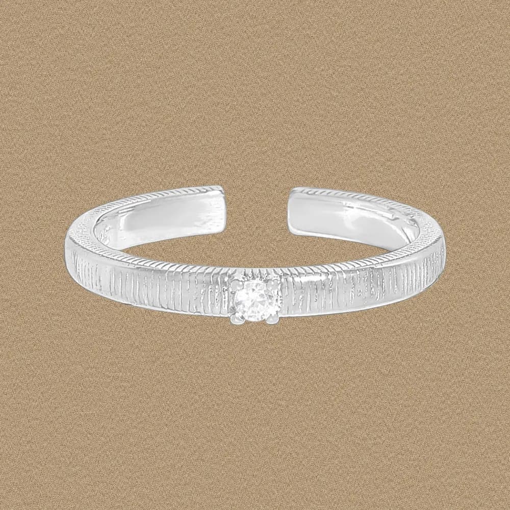Open-ended sterling silver ring with vertical ribbing and a small central diamond.