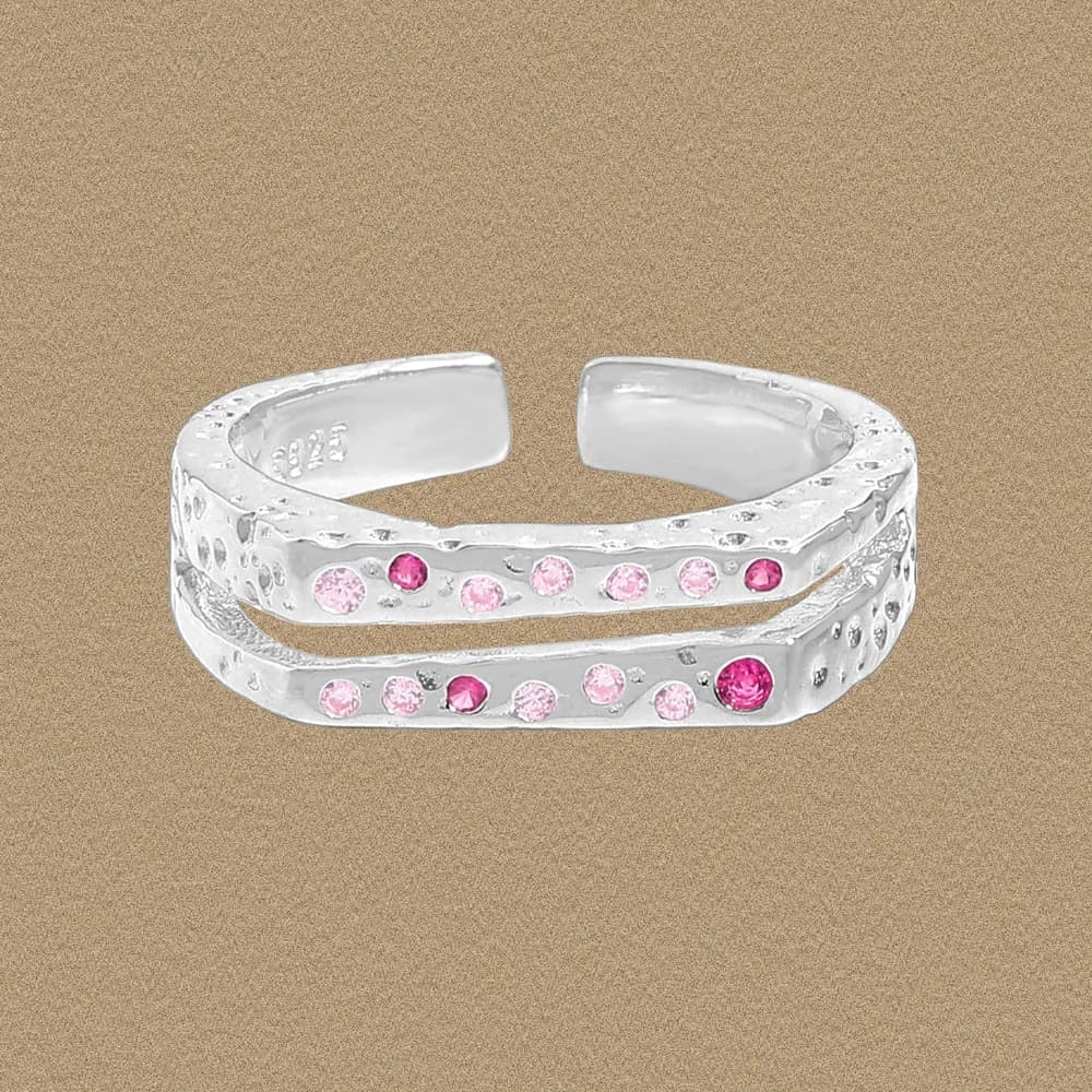 Polished sterling silver double-band ring with pink stones, set on a beige background.