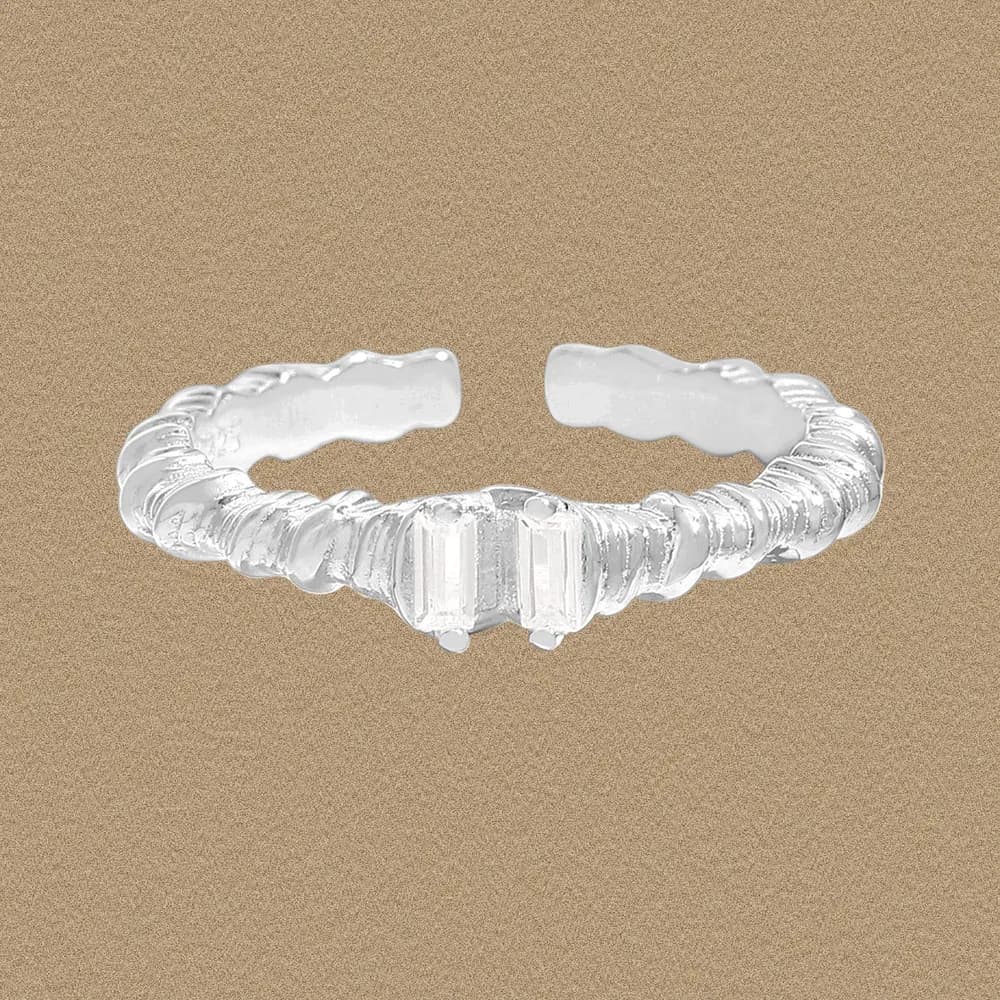 Open ribbed sterling silver ring with a textured band on a tan background
