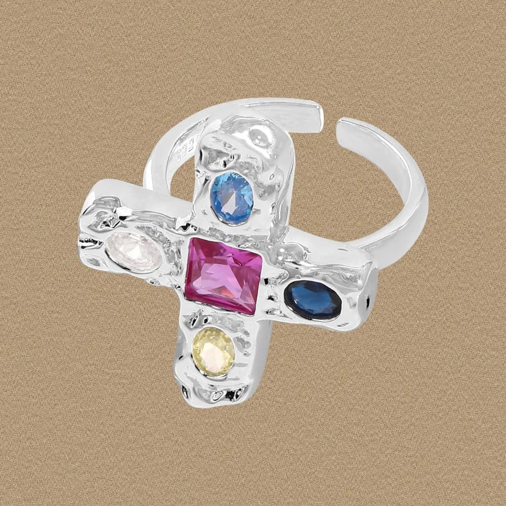 Close-up of a polished sterling silver cross ring with multicolor gemstone bezels set in a raised cross motif.