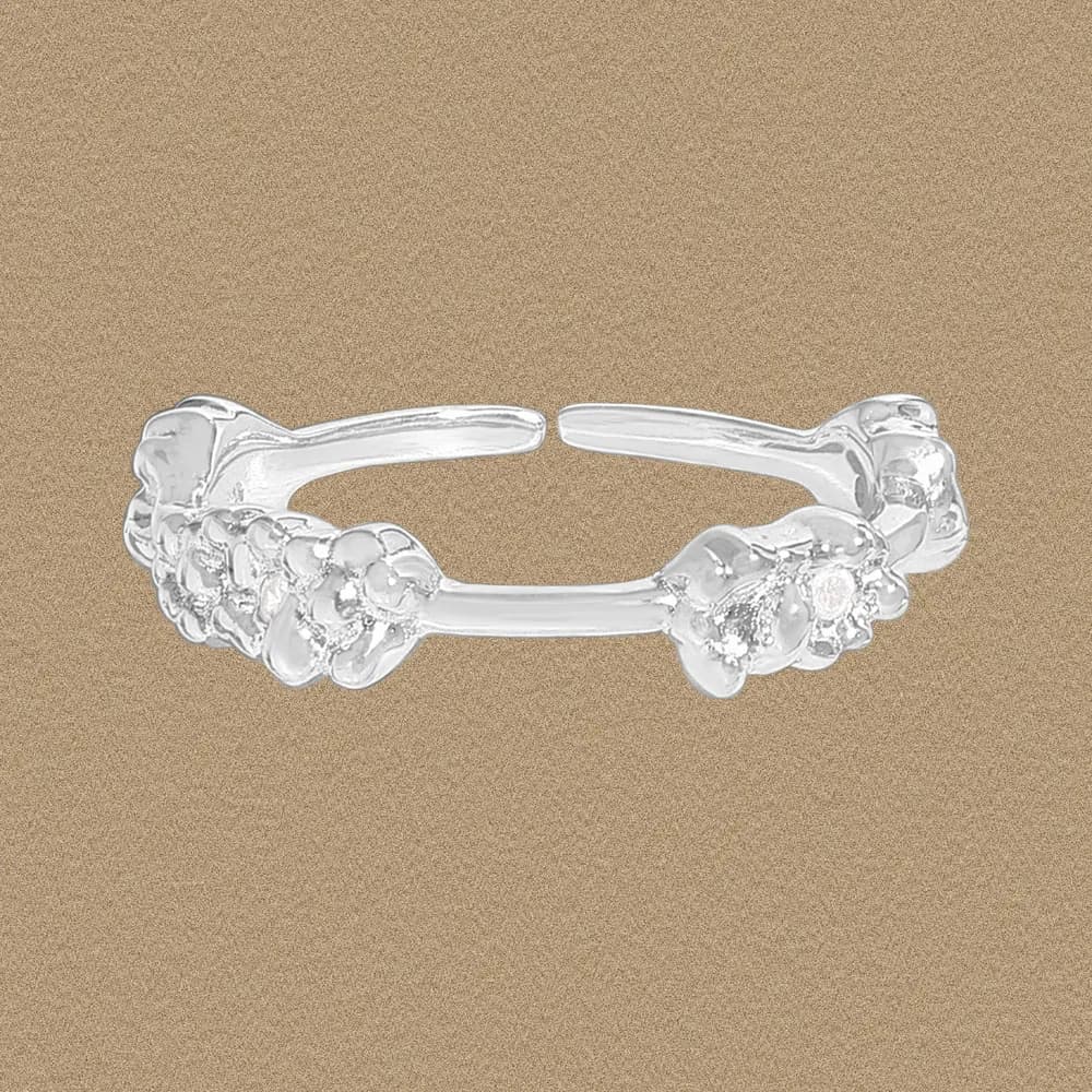 Open sterling silver ring with two bubble-cluster ends on a beige background.