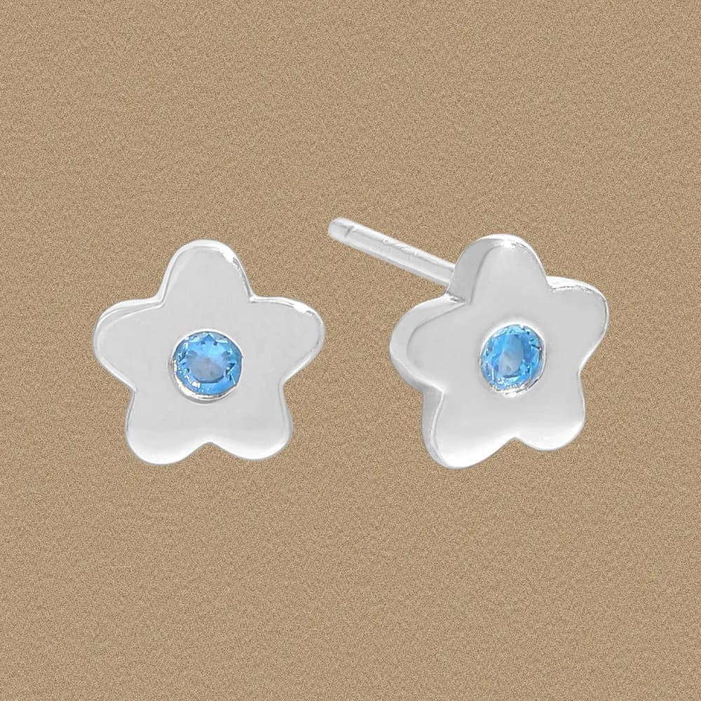 Silver flower-shaped stud earrings with a blue center gemstone on a plain background.