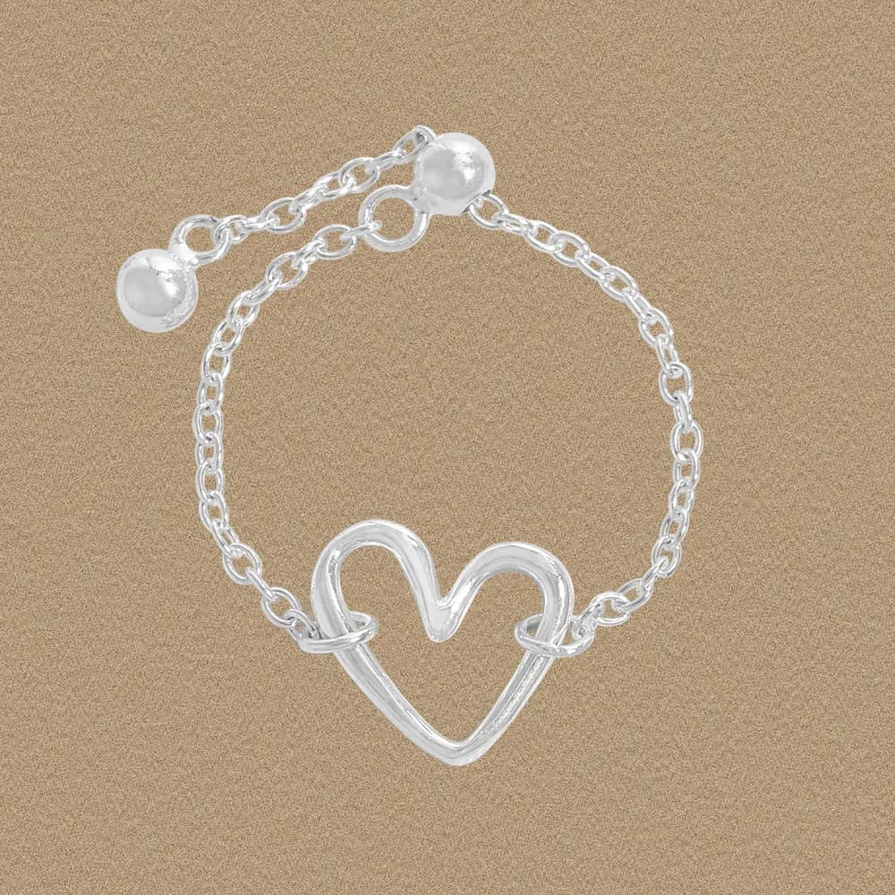 Polished sterling silver ring with an open heart design on a warm-toned background.