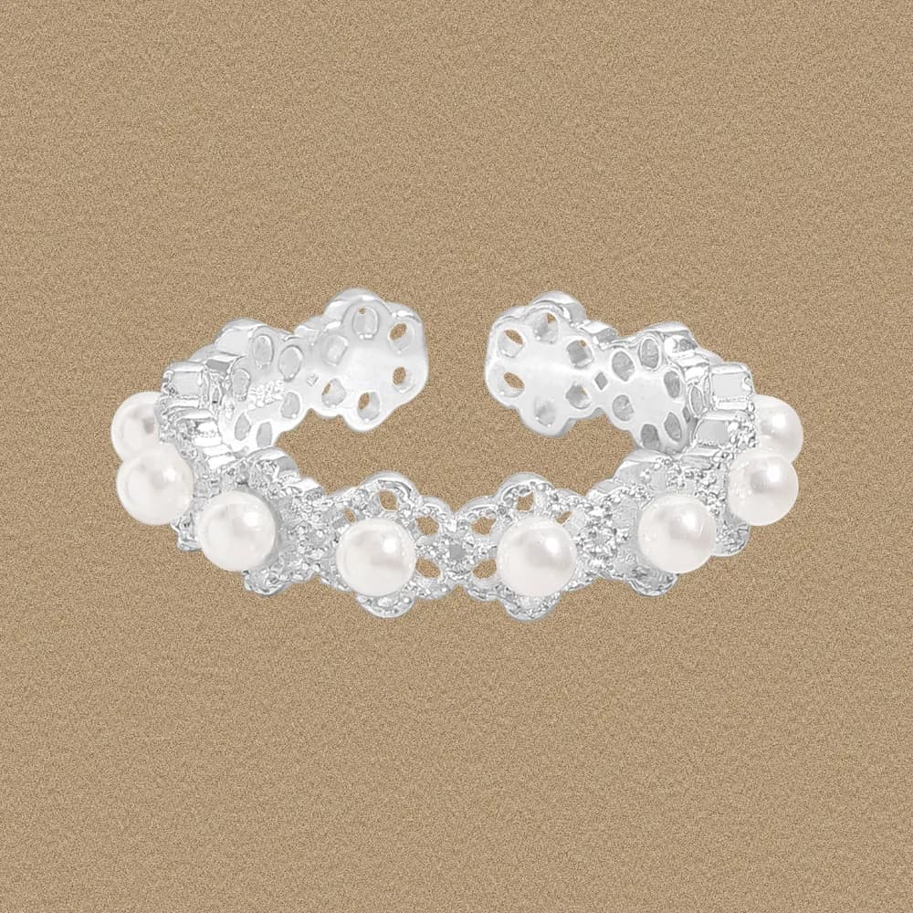 Sterling silver ring with pearl beads and lace-like openwork sits on a neutral background.