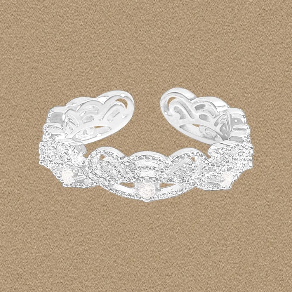 Polished sterling silver heart filigree ring with pavé accents photographed on a warm background.