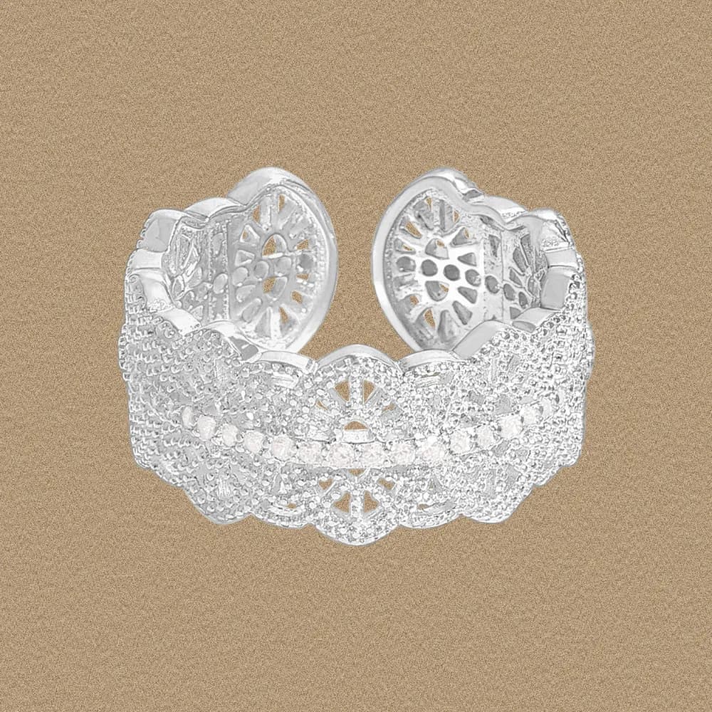 Wide lace filigree ring in polished sterling silver on a warm beige background.