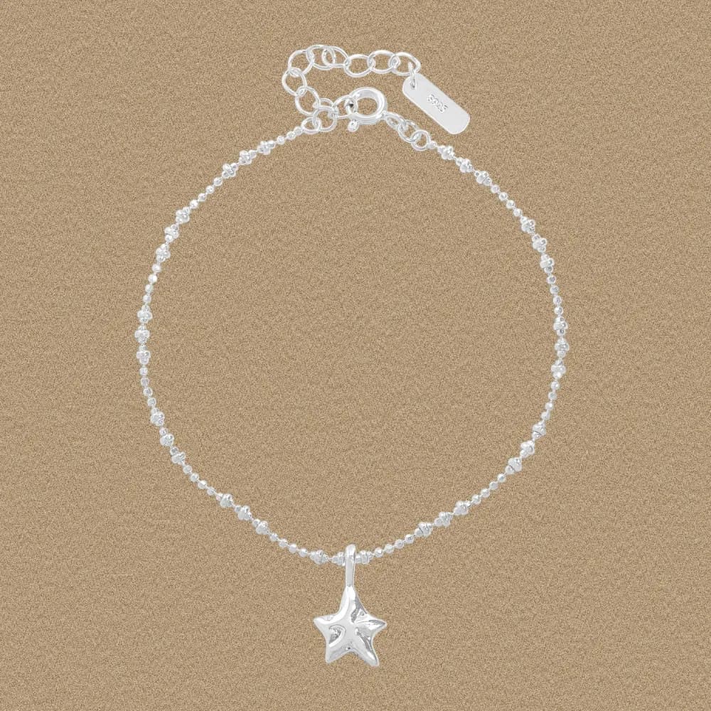 Sterling silver beaded bracelet with a small star charm pendant on a neutral background.