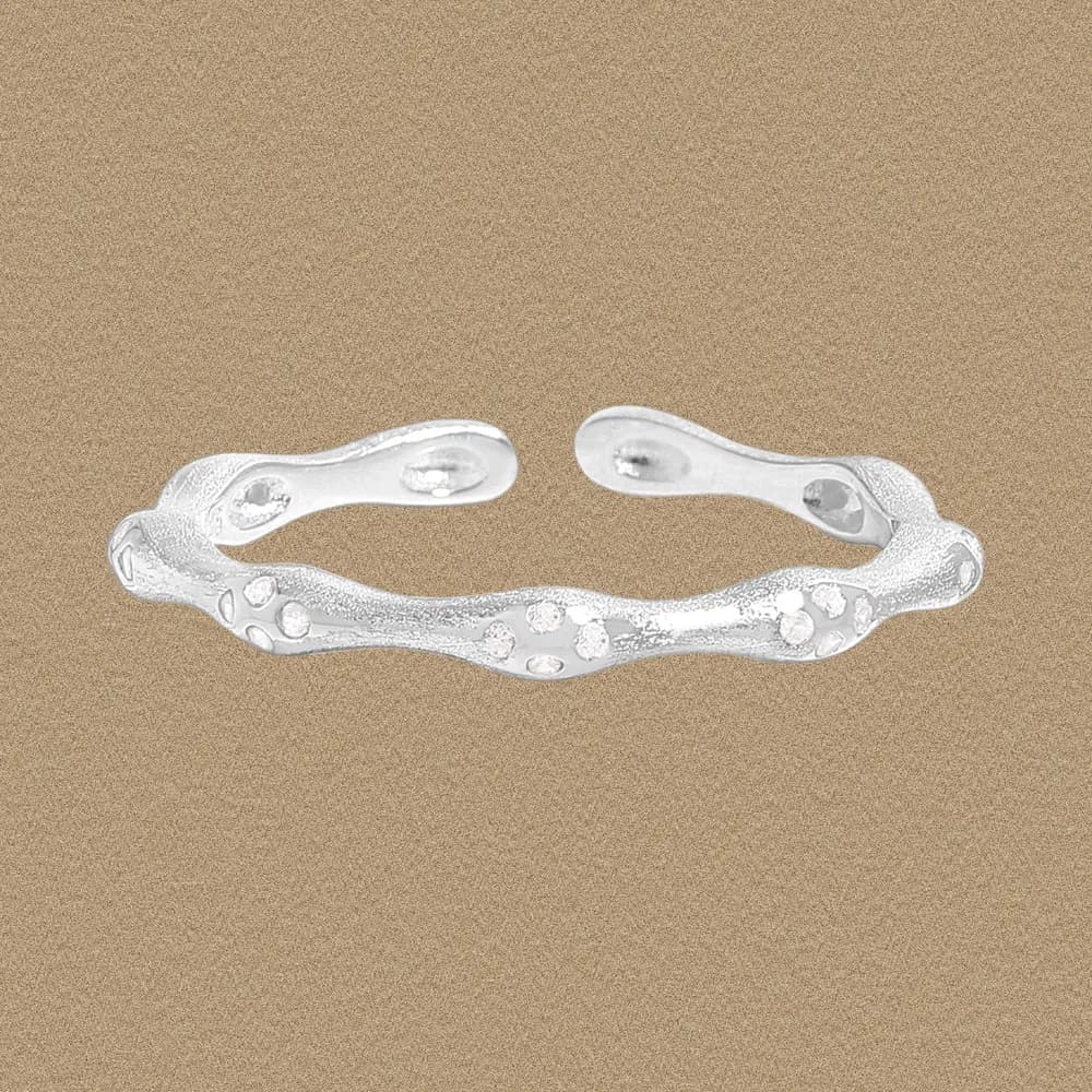 Open-ended sterling silver ring with a wavy textured band and scattered bead-like accents.