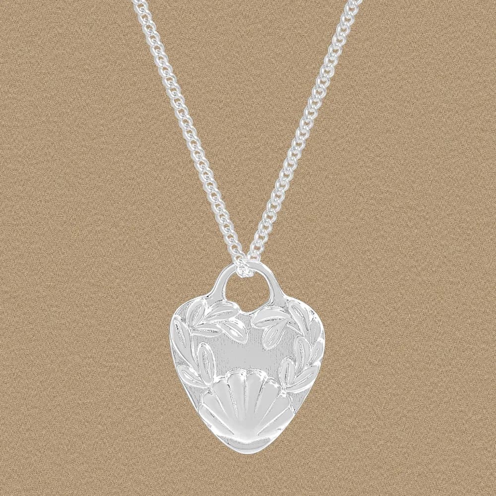 Polished sterling silver heart pendant with engraved leaf and shell details on a curb-chain necklace.