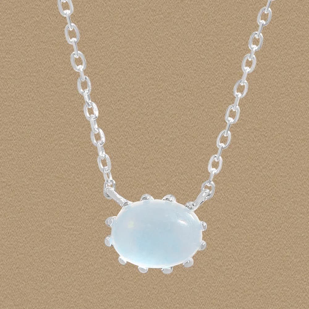 Sterling silver moonstone pendant on a polished chain against a light brown background.