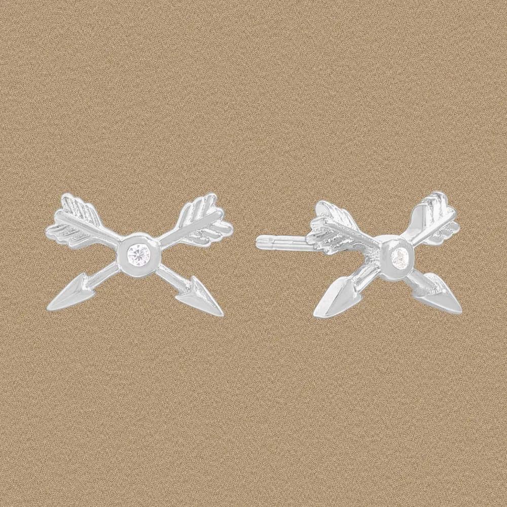 Pair of polished sterling silver arrow-cross stud earrings with small central gemstone on a neutral background.