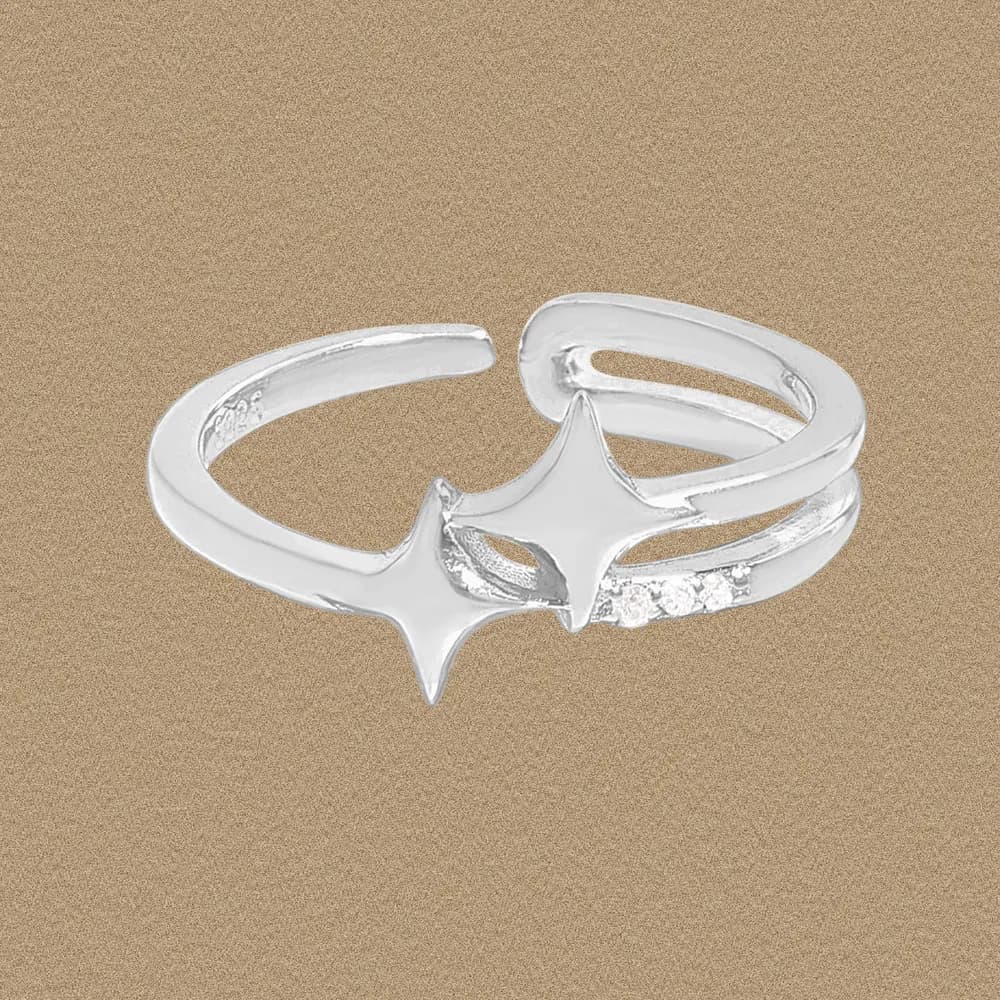 Polished sterling silver open ring with two star motifs and pavé accents on a warm, sandy background.