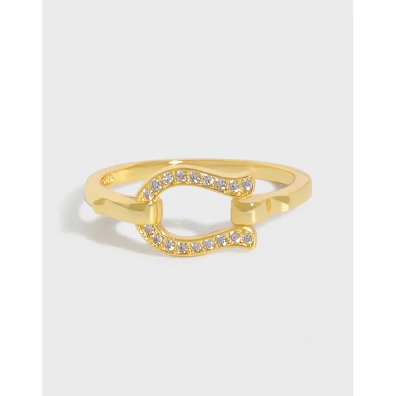 Polished ring with double curved horseshoe shape and crystal pavé accents on a light background.