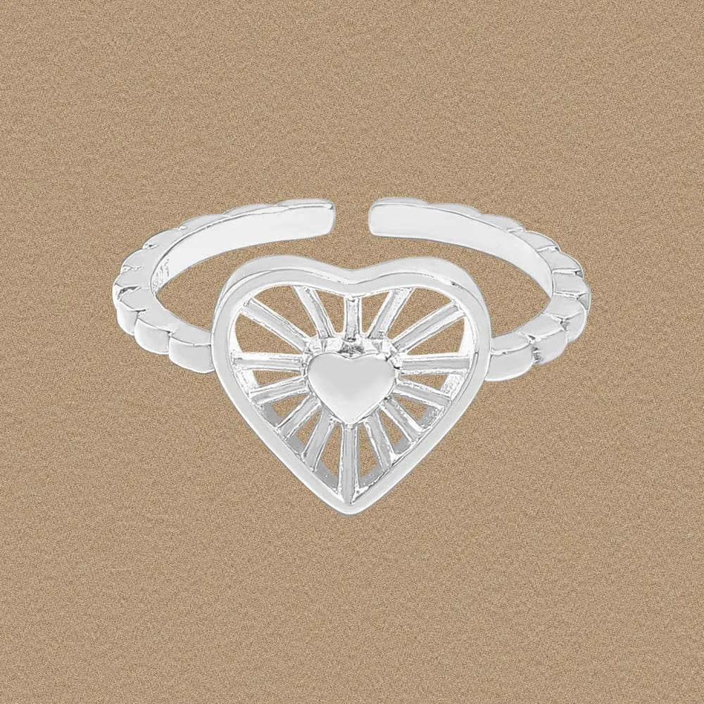 Polished sterling silver ring with a heart-shaped center and sunburst rays on a neutral background.